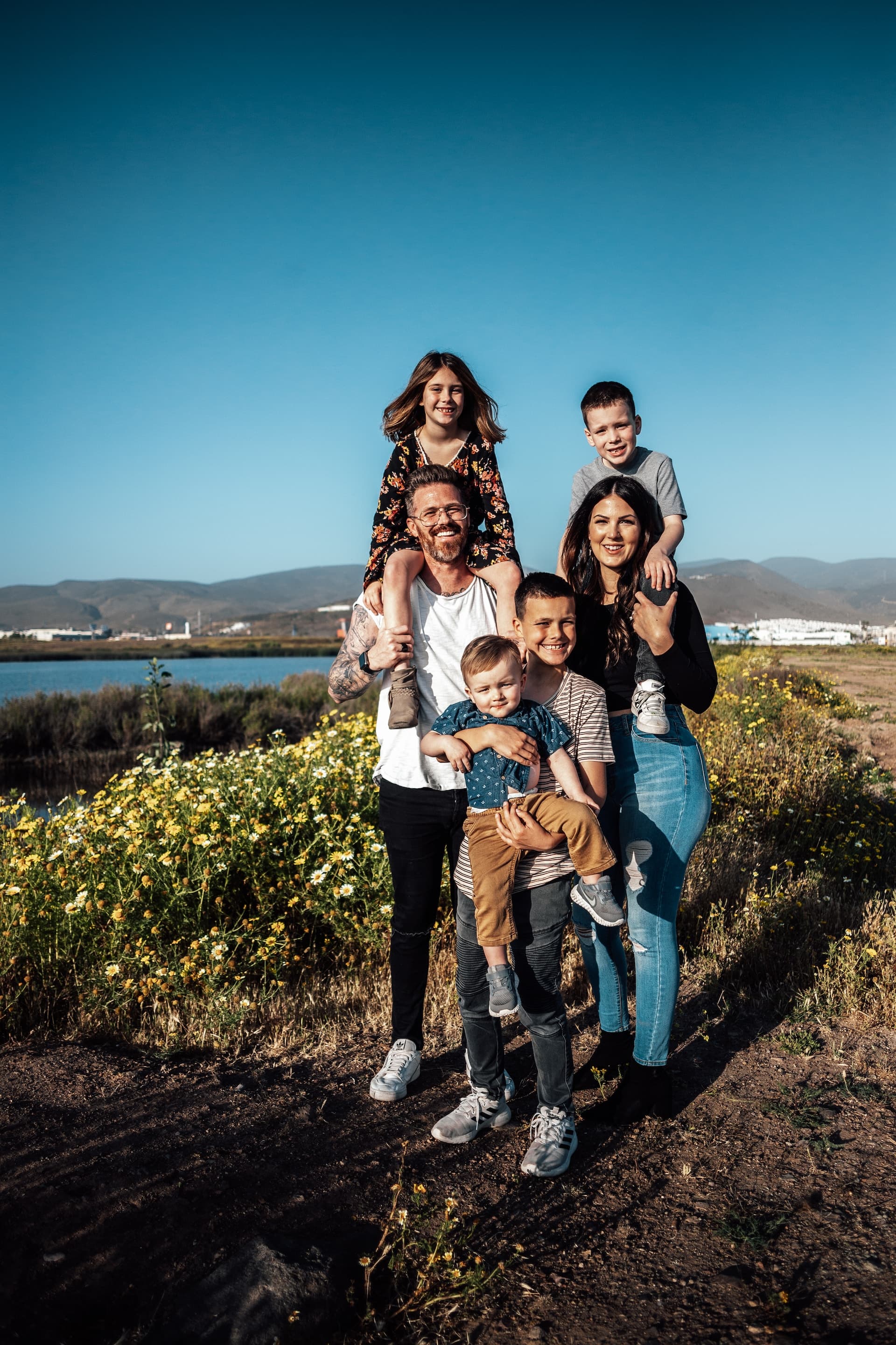 Mom, dad, and 4 kids posing for photo with stunning landscape on the background.